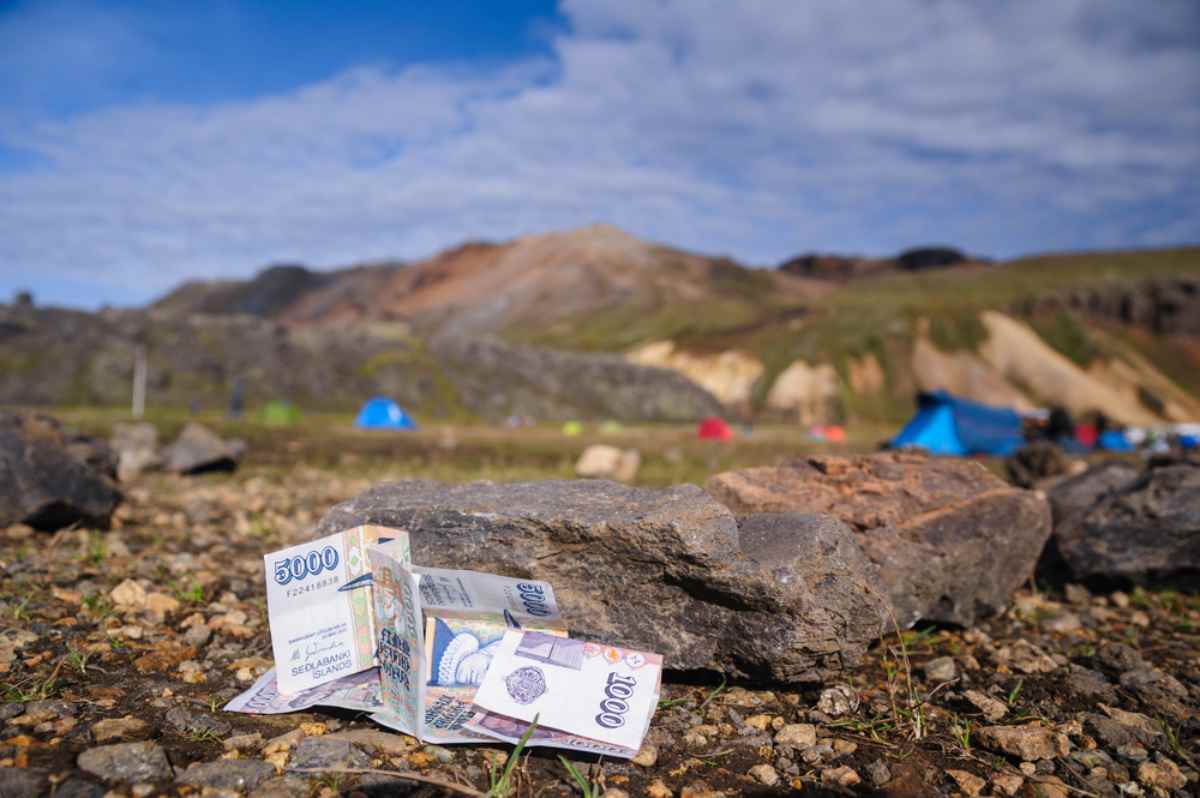 Un paio di banconote islandesi appaiono accanto a diverse rocce in quello che sembra un campeggio islandese.