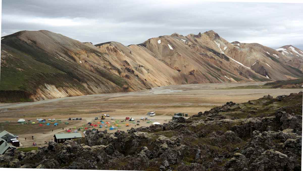 Vue aérienne d'un véhicule blanc traversant ce qui semble être une route islandaise non goudronnée remplie de sable noir et de cendres.
