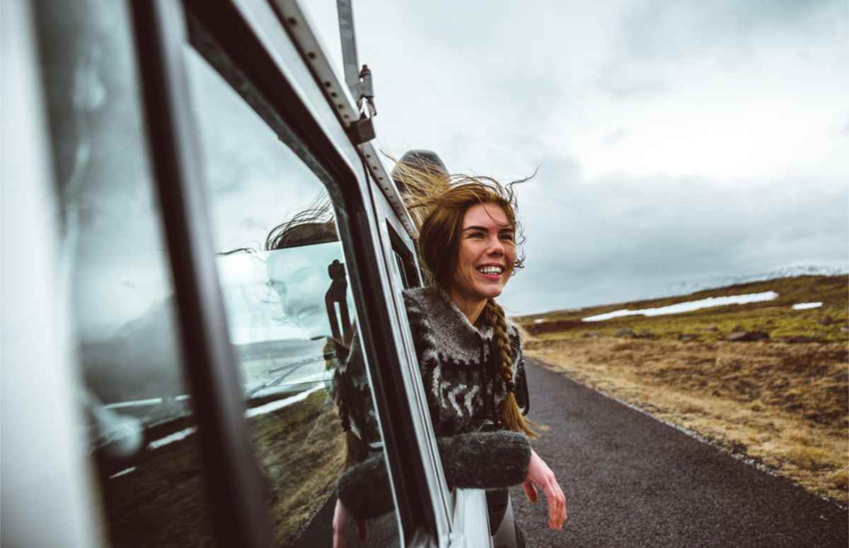 Cute woman sticking her head out of her rental camper to enjoy the wind