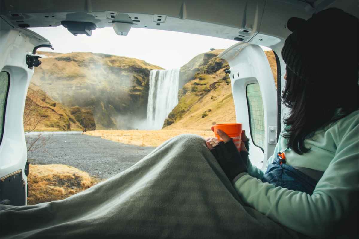 Tourist watching a waterfall from the back of her campervan