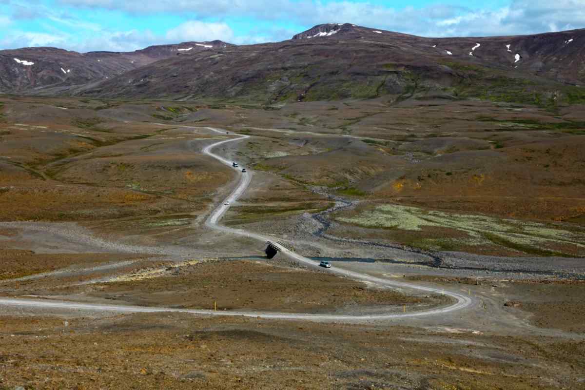 F35 road in Iceland Scenic Icelandic F-road winding through remote highlands, with several 4x4 vehicles driving across rugged terrain in summer.
