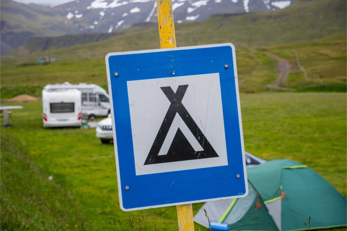 Touristin in ihrem gemieteten Camper in Island nahe einem wunderschönen Wasserfall