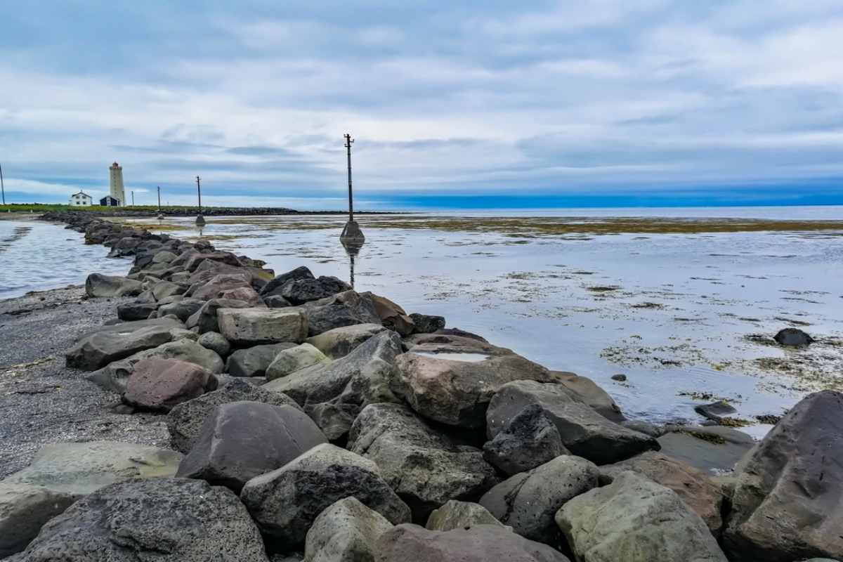 Lighthouse and rocky shoreline in Reykjav&iacute;k under a cloudy sky