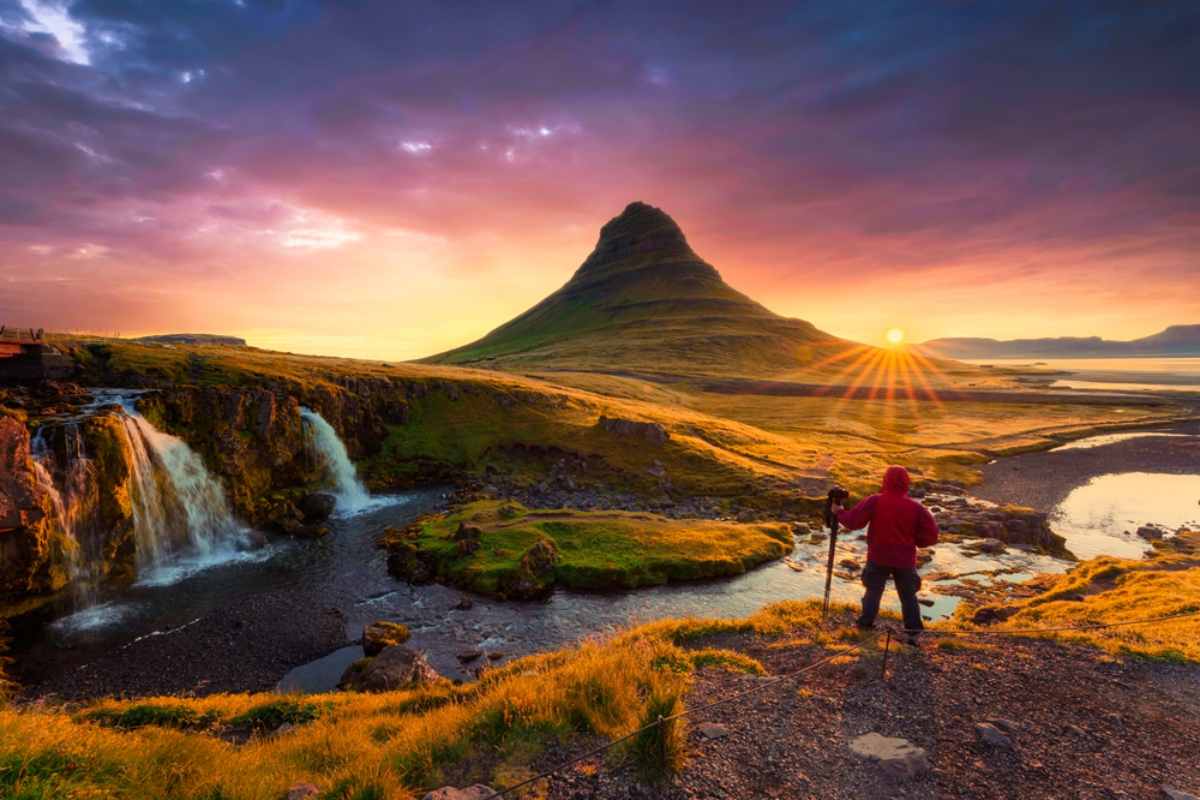 Photographer at Kirkjufellsfoss waterfall with Kirkjufell at sunset in Iceland