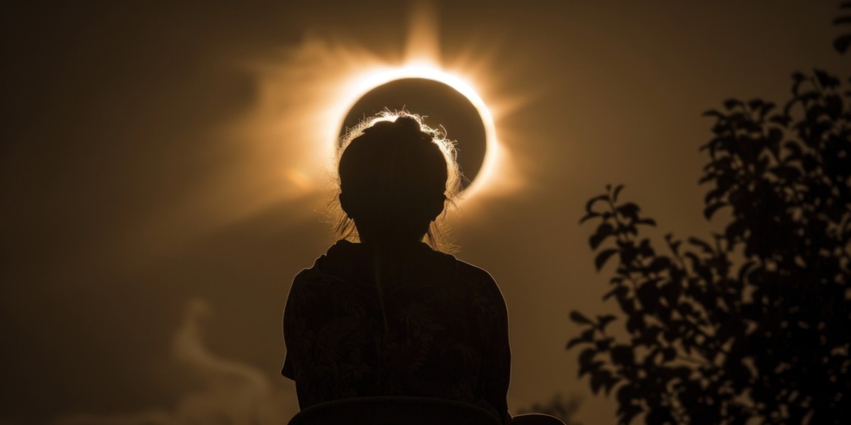 Silhouette d’une personne observant une éclipse solaire avec la couronne du soleil brillant derrière elle