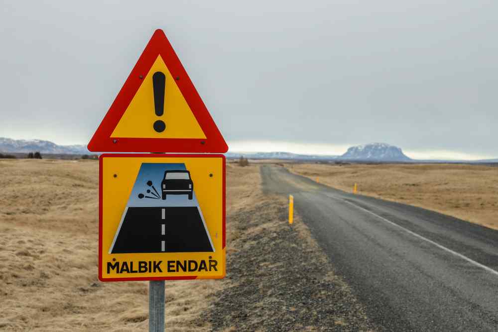Gravel roads in Iceland Icelandic road sign warning that the paved road is ending and gravel begins.