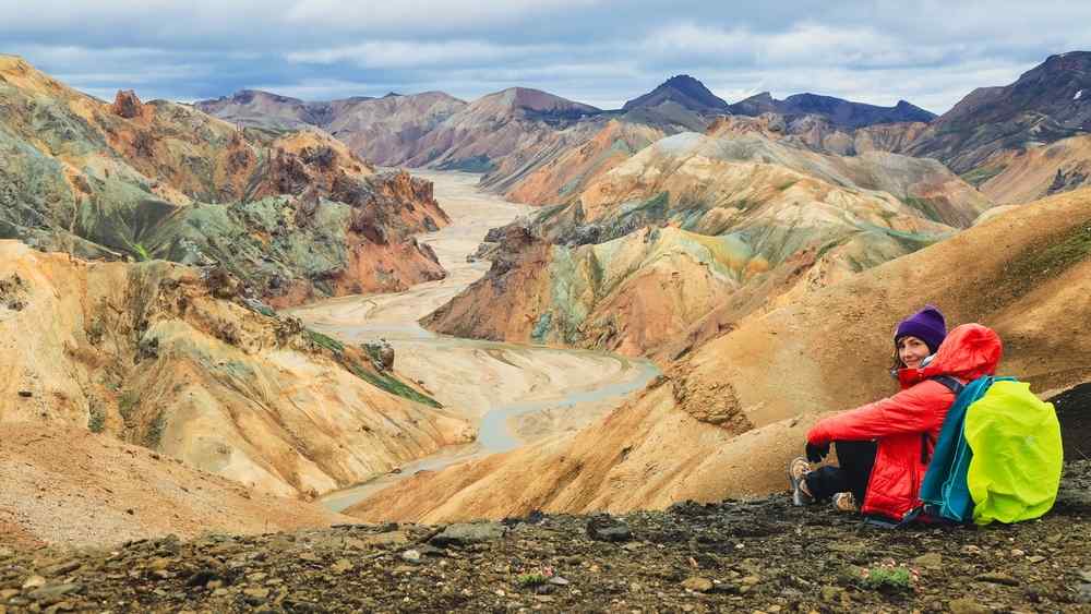 Iceland's Landmannalaugar Hiker resting above the colorful rhyolite mountains and volcanic valleys of Landmannalaugar in the Icelandic Highlands.