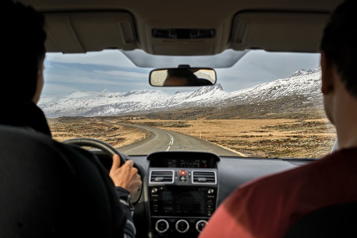 Tourists heading down the Ring Road in Iceland in a campervan, passing the amazing view of mountains covered with snow