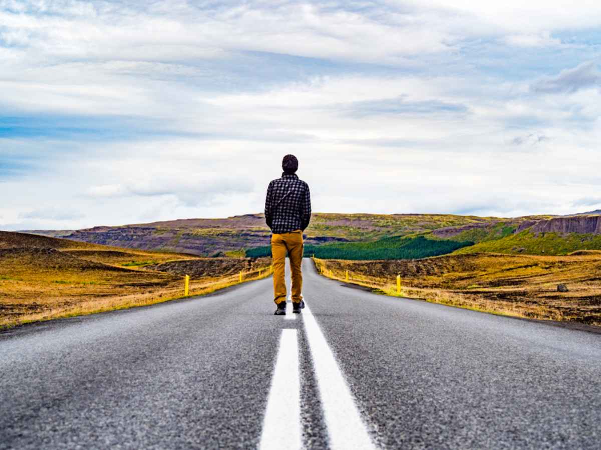 Mann geht eine einsame Straße in Island im Herbst entlang
