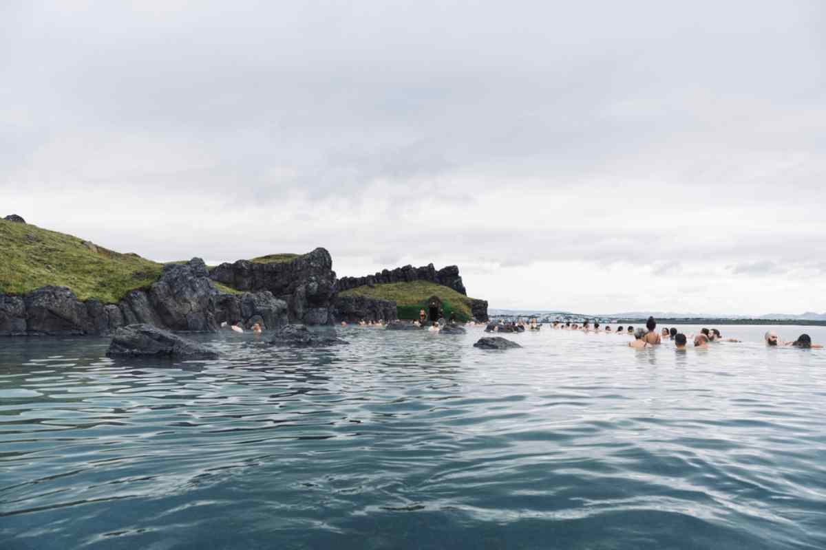 Tourist:innen baden in einer natürlichen Thermal-Lagune in Island.