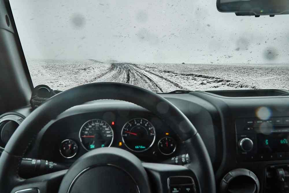 Fahren in Island im Winter Blick aus dem Inneren eines Fahrzeugs, das bei schlechter Sicht auf einer verschneiten Straße in Island fährt.