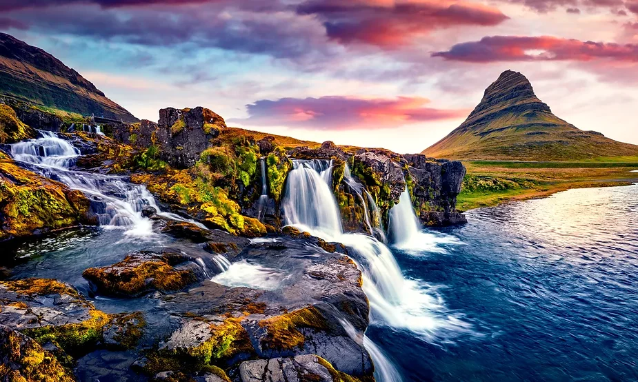Malereischer Blick auf den Kirkjufellsfoss-Wasserfall mit üppigem Grün und dem Kirkjufell-Berg im Hintergrund während des Sonnenuntergangs, isländisch