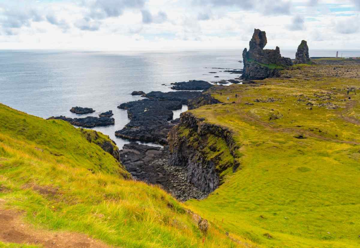 Vista general de un acantilado con rocas oscuras y vegetación verde en la península islandesa de Snæfellsnes.