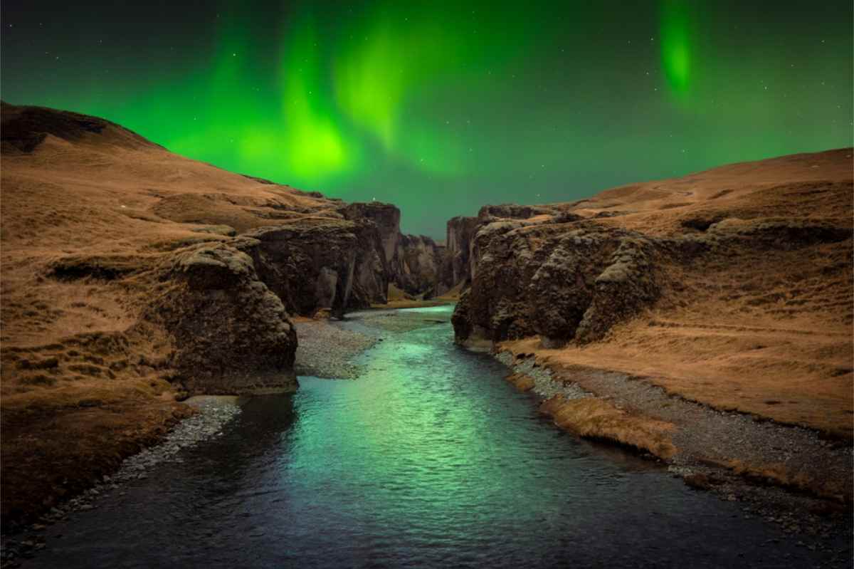 Imagen impresionante de un cañón en Islandia con una aurora verde