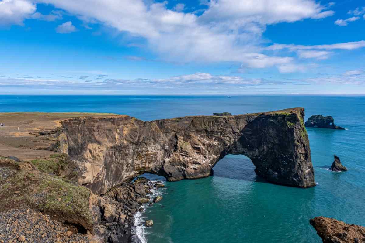 Vista del arco rocoso de Dyrhólaey junto al mar en el sur de Islandia en un día soleado.