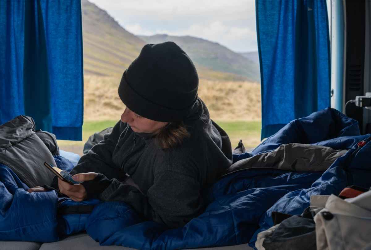 Viajera relaj&aacute;ndose dentro de su camper mientras mira el m&oacute;vil