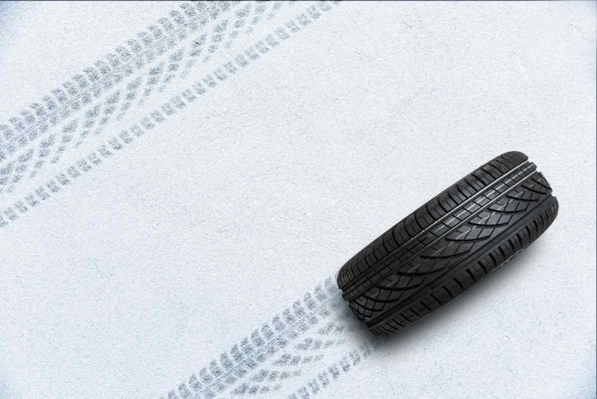 Neum&aacute;tico negro con dibujo profundo dejando huellas sobre una superficie nevada.