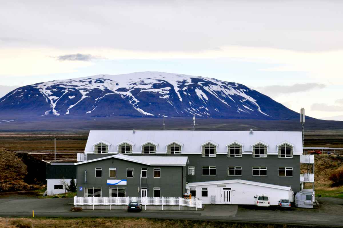Hotel rural en Islandia con monta&ntilde;as nevadas al fondo en un d&iacute;a nublado.