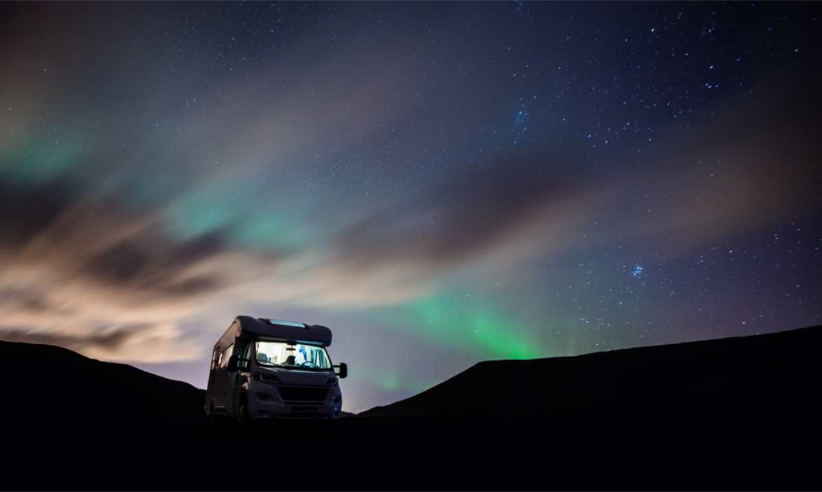 Autocaravana aparcada con las auroras boreales brillando sobre ella