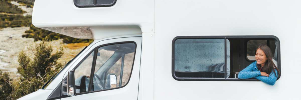 Mujer asomada a la ventana de su autocaravana de alquiler