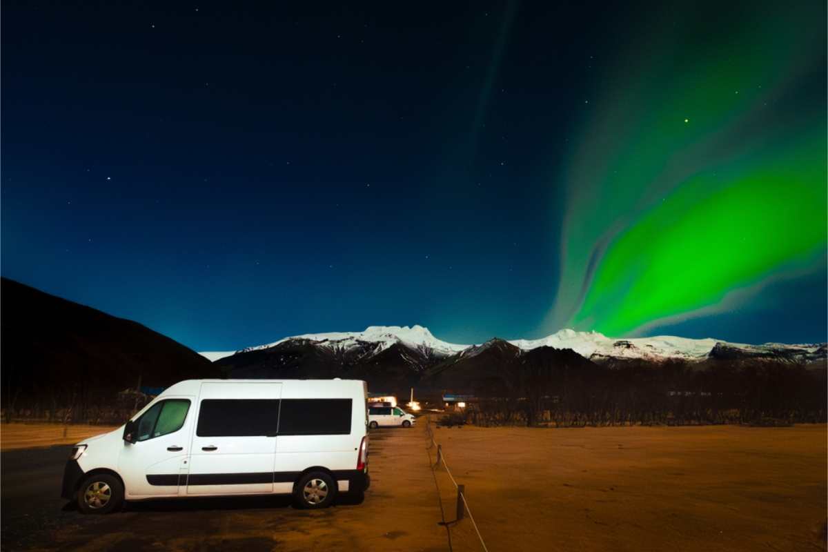 Auroras boreales brillando sobre una camper y un camping de autocaravanas en Islandia