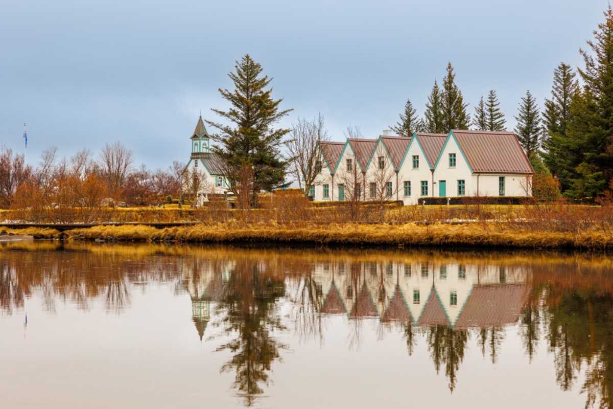 Parque nacional Þingvellir Edificios tradicionales reflejados en aguas tranquilas en el parque nacional de Þingvellir, en Islandia, durante el otoño