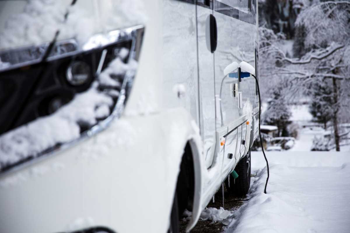 Invierno en Islandia Autocaravana cubierta de nieve aparcada durante el invierno con un cable de conexión eléctrica conectado en un camping