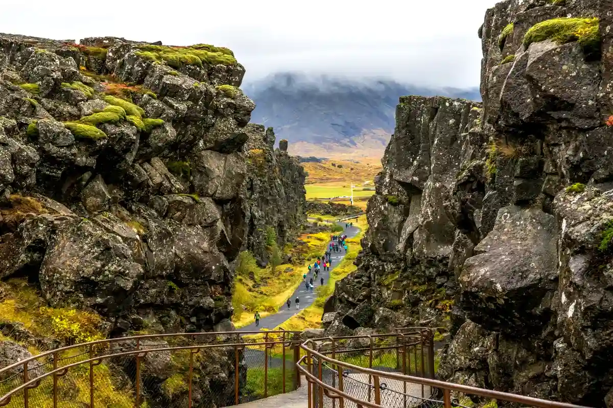 Un sendero panor&aacute;mico que serpentea a trav&eacute;s de acantilados escarpados cubiertos de musgo y rocas en el Parque Nacional Thingvellir en Islandia.