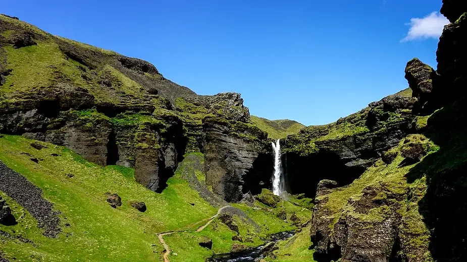 Vista de la majestuosa catarata Kvernufoss desde atr&aacute;s, enmarcada por formaciones rocosas en Islandia.
