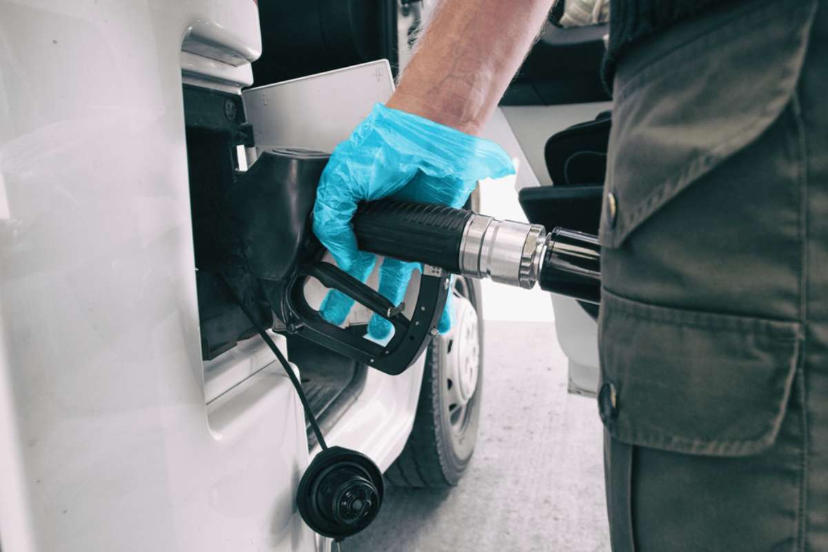 Gros plan d&rsquo;une main gant&eacute;e faisant le plein d&rsquo;un camping-car avec un pistolet de pompe dans une station-service.