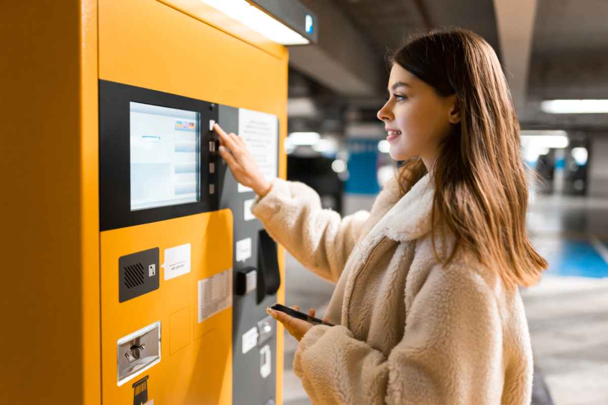 Une jeune fille brune paie à une machine de garer après avoir garé son véhicule à l'intérieur.