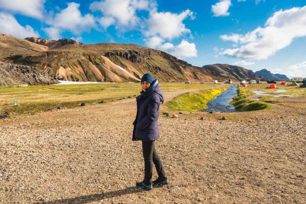 Coût de l’hébergement en Islande Voyageuse au camping de Landmannalaugar avec tentes, ruisseau et collines de rhyolite.
