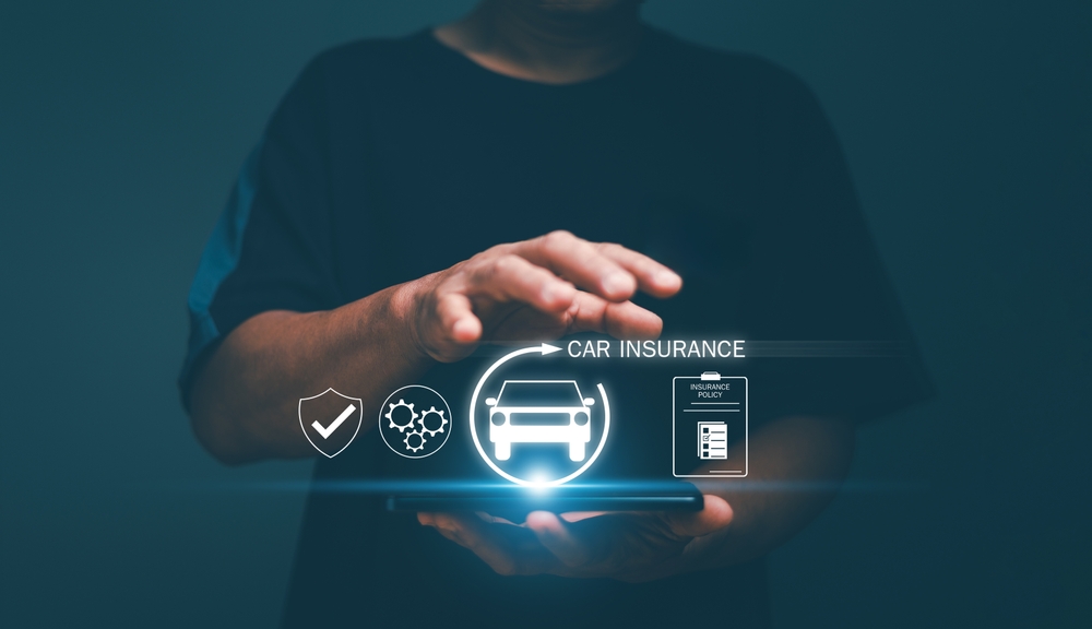 Personne tenant un t&eacute;l&eacute;phone avec des ic&ocirc;nes lumineuses d&rsquo;assurance automobile et des symboles num&eacute;riques de police au-dessus de l&rsquo;&eacute;cran