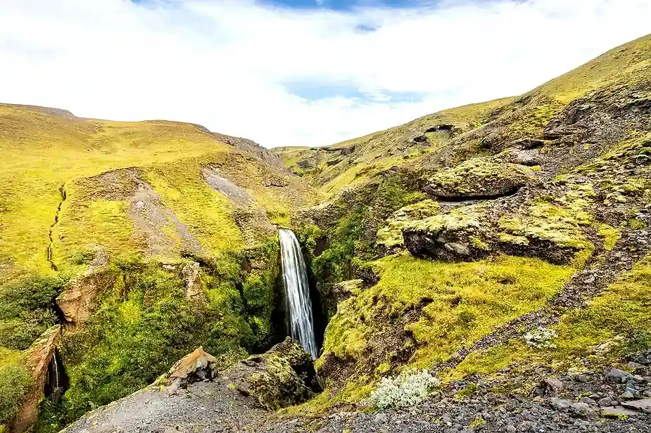 La cascade de Nauthúsafoss qui coule dans une gorge étroite entourée de collines verdoyantes et d'un terrain rocheux en Islande. Le paysage pittoresqu