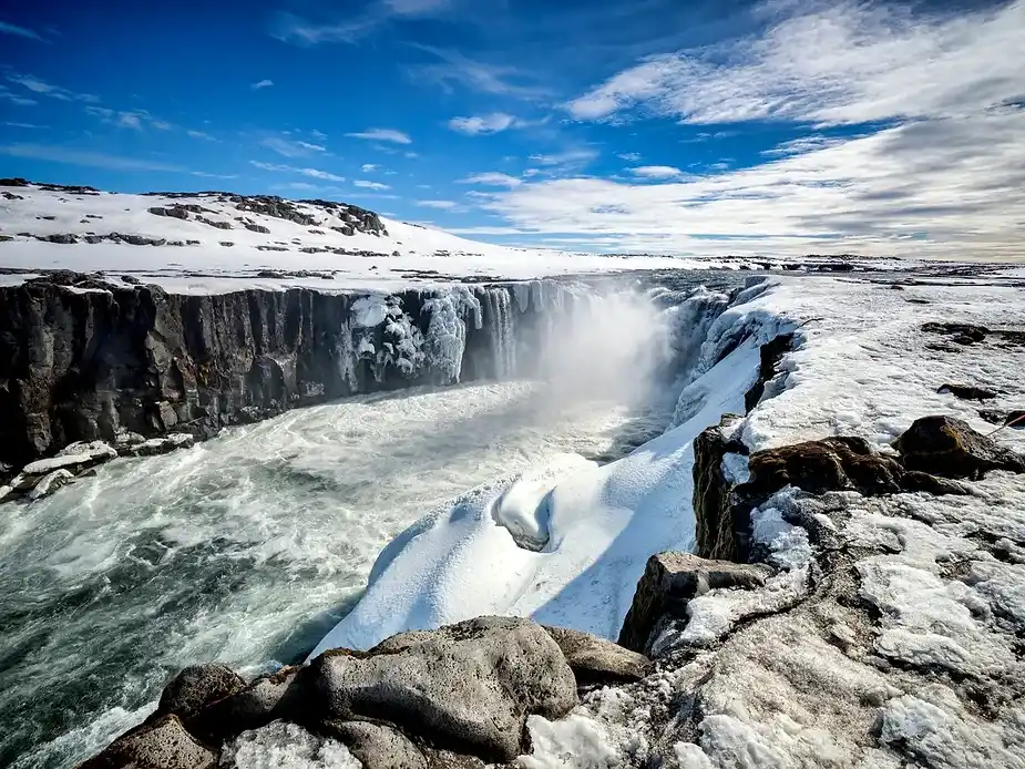 Cascade glacée de Selfoss au milieu du paysage enneigé de l'hiver en Islande Paysage enneigé entourant la cascade de Selfoss alors que l'eau glacée s'écoule sur les falaises de basalte sous un ciel bleu clair, Islande en hiver.
