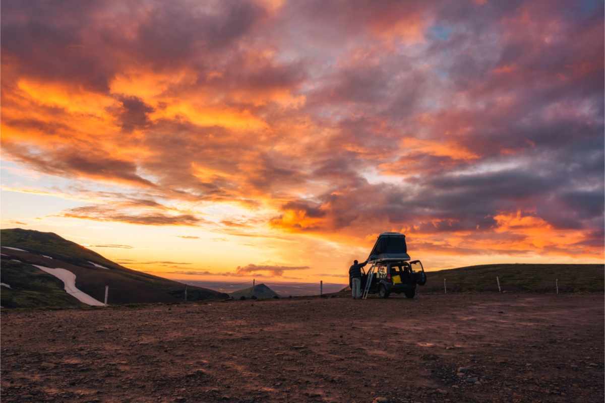 Periodo migliore per percorrere la Ring Road Camper con tenda sul tetto sotto un cielo dorato al tramonto