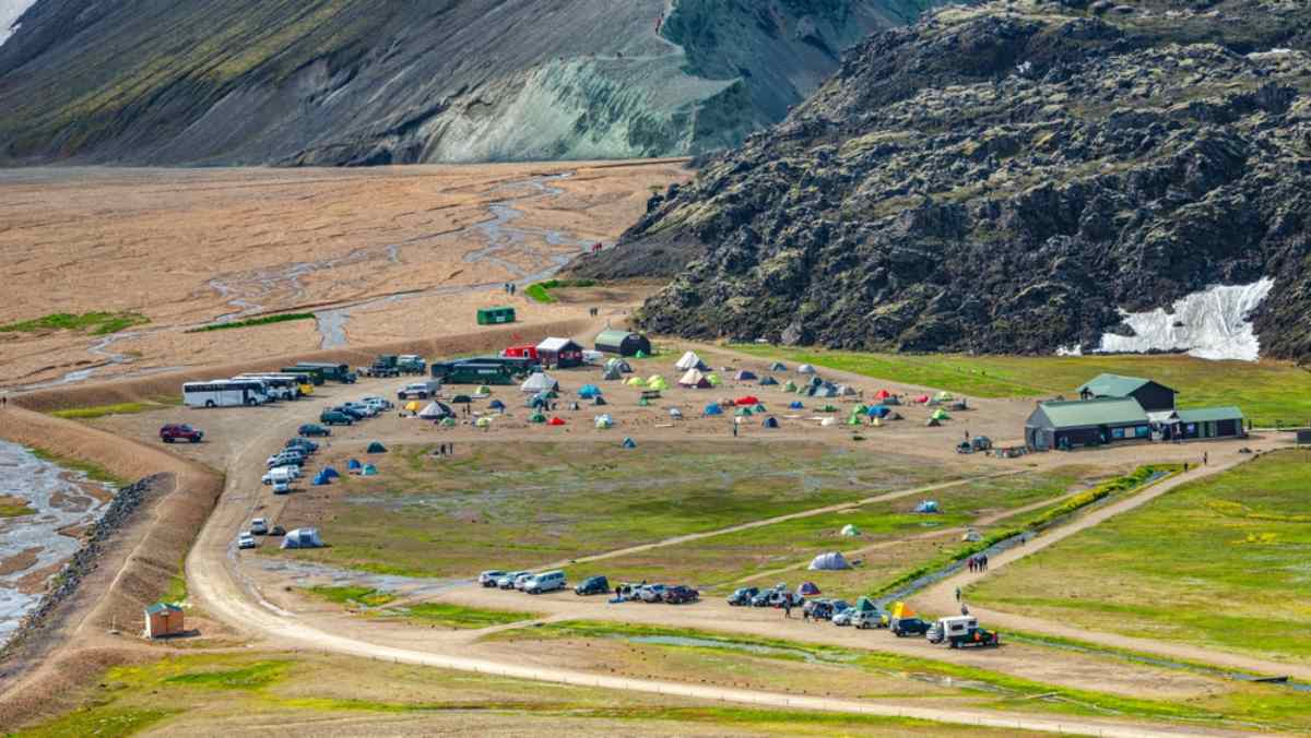 Campeggio con tende, auto e un edificio di servizi negli altopiani islandesi.