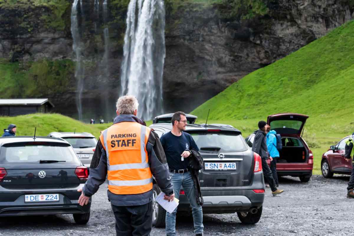 Addetti al parcheggio che dirigono le auto alla cascata Seljalandsfoss in Islanda.