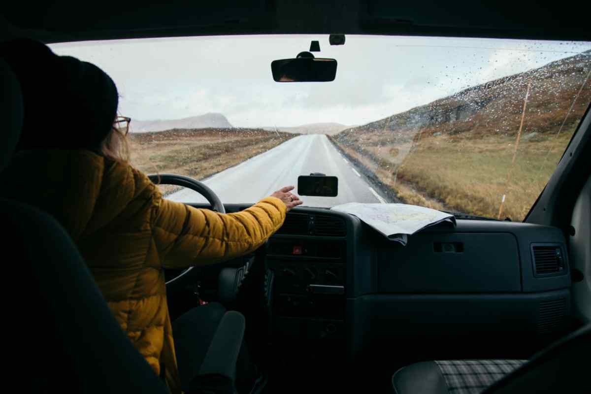 Vista dall&rsquo;interno di un&rsquo;auto con un viaggiatore alla guida sotto la pioggia nei paesaggi islandesi.