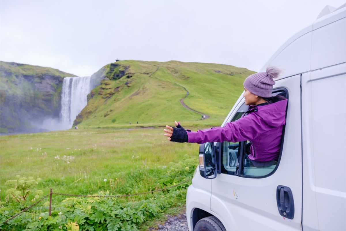 Turista nel suo camper a noleggio in Islanda vicino a una splendida cascata