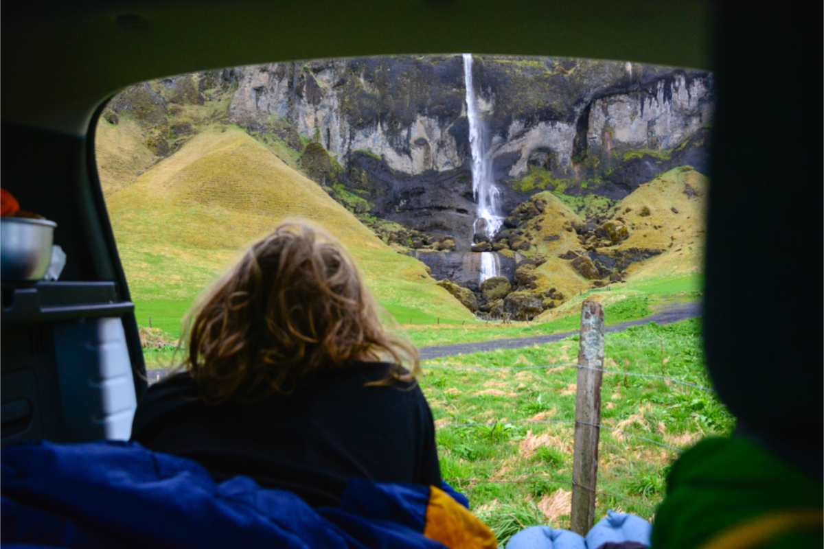 Turista che si gode una magnifica cascata mentre &egrave; sdraiata nel suo campervan