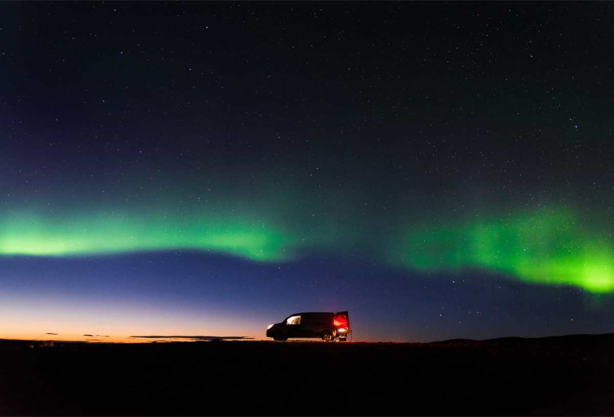 Campervan parcheggiato sotto un&rsquo;aurora boreale verde