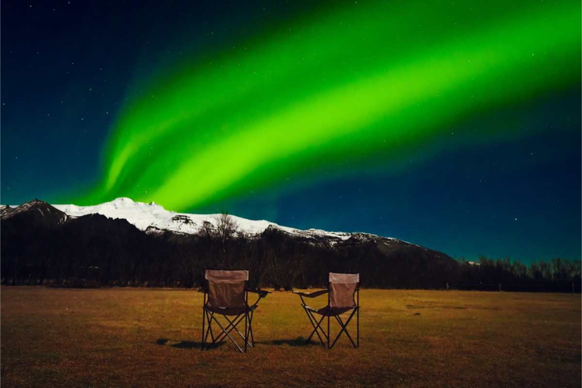 Due sedie da campeggio nella natura selvaggia dell&rsquo;Islanda con l&rsquo;aurora boreale