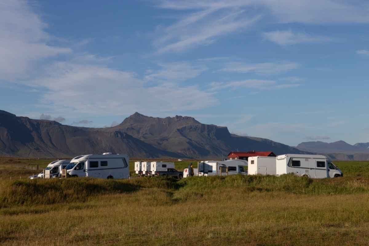 Camper parcheggiati in un campeggio in Islanda con montagne sullo sfondo