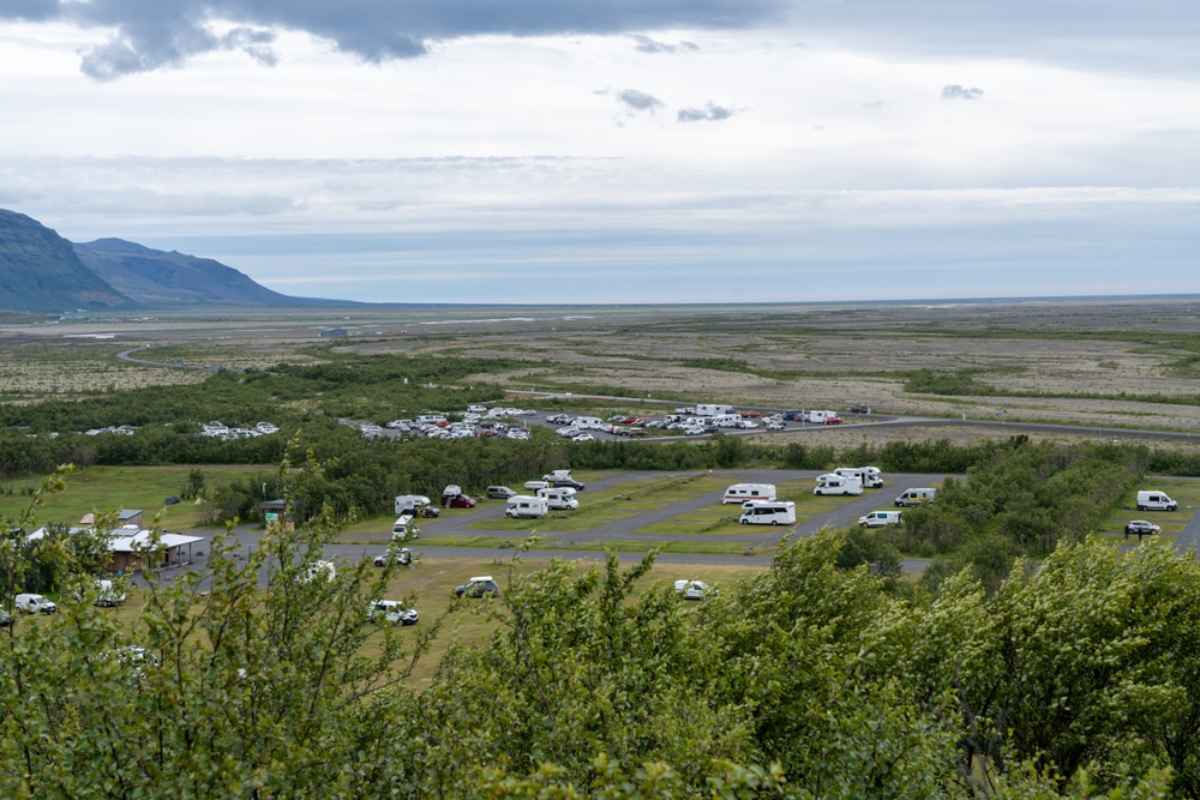 Vista sull'area campeggio di Vatnajokull con camper, caravan e ampio paesaggio sullo sfondo