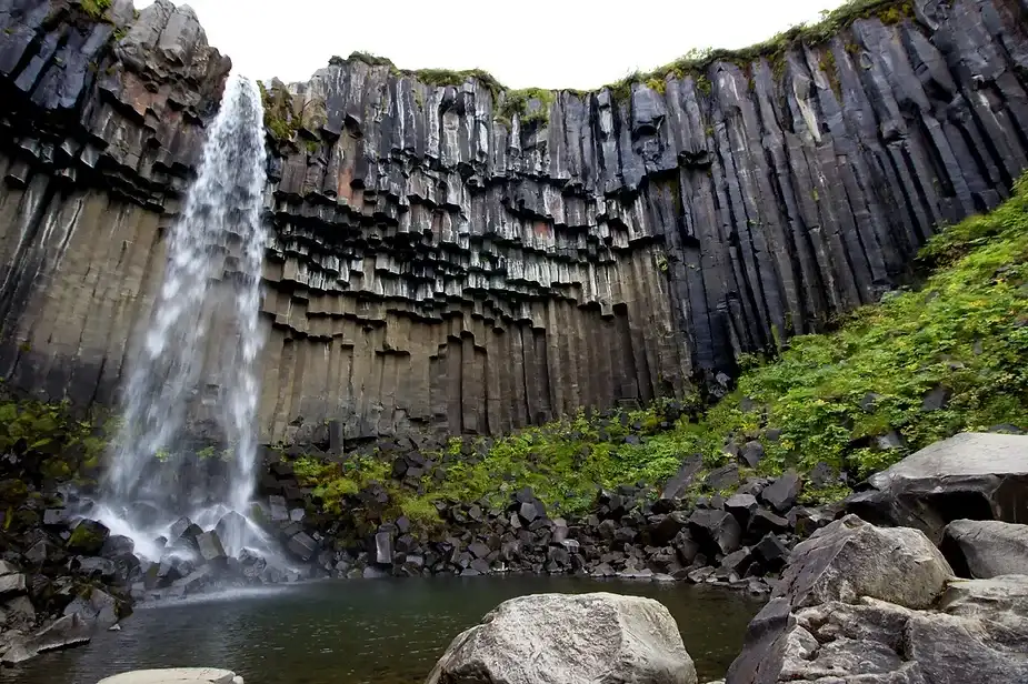Una maestosa cascata che scorre lungo le colonne di basalto scuro di Svartifoss in Islanda. Le formazioni rocciose verticali creano uno sfondo suggest
