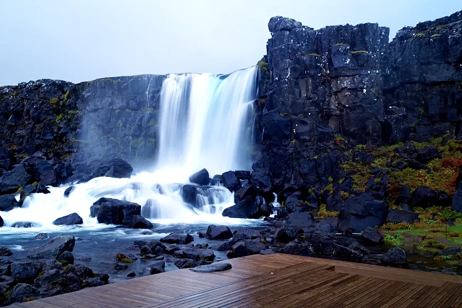 Un passerella in legno che porta alla cascata di Öxarárfoss, che scorre di fronte alle scogliere vulcaniche nel Parco Nazionale di Thingvellir, in Isl